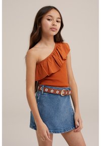 Top arancione a spalla unica con dettagli a volant, abbinato a una gonna di jeans blu chiaro e una cintura marrone con motivi di fiori bianchi.