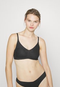 Black bra with a v-neck design and thin straps. The fabric features a subtle wave texture, offering a smooth and lightweight appearance.
