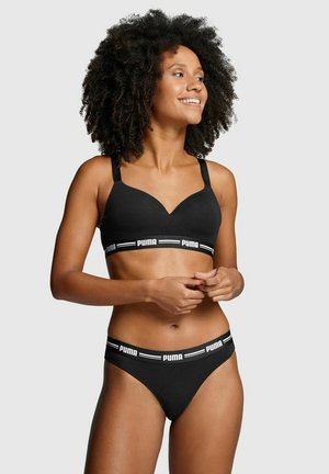 Schwarzer Sport-BH mit V-Ausschnitt, gepolsterten Cups und verstellbaren Trägern. Kombiniert mit schwarzen Bikiniunterhosen mit einem weißen Logo-Bund.