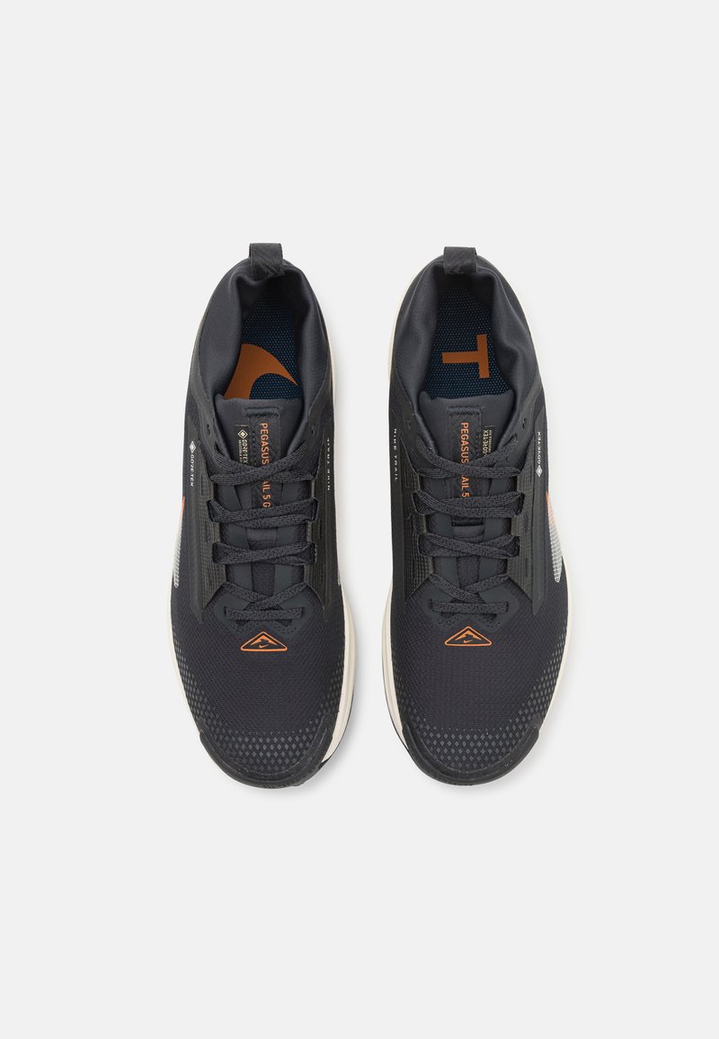Zapatillas deportivas negras con parte superior de malla texturizada, detalles en naranja y una suela acolchada. Cuentan con cordones y una lengüeta en el talón.