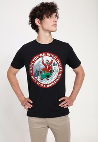 Camiseta de algodón negra con un gráfico colorido de un esqueleto vestido de Santa en un trineo, rodeado de texto en un borde circular rojo.