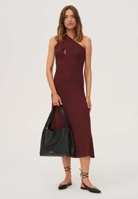 Bordó bordázott ruha egyvállas kialakítással, elöl kivágással. Fekete bőr nagy táskával és lapos fekete cipővel párosítva.