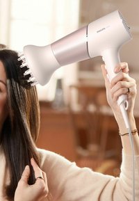 Asciugacapelli Philips con finitura bianca e rosa, design ergonomico e attacco per diffusore. Capelli acconciati con una texture liscia e dritta.