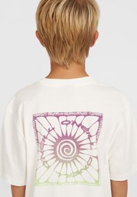 Biela bavlnená tričko s krátkymi rukávmi a voľným strihom, na chrbte so spirálovým a geometrickým dizajnom v purpurovej a zelenej farbe.