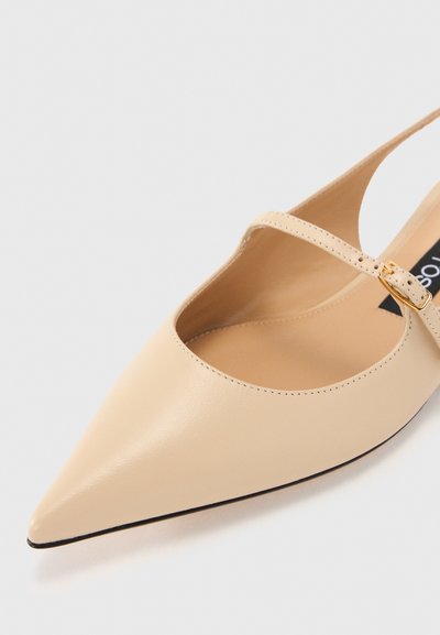 Pantofii din piele bej, cu vârf ascuțit, au un design cu decupaj pe lateral și o curea subțire la gleznă, adornată cu o cataramă în tonuri de aur. Textură netedă și design elegant.
