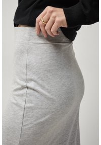 Lichtgrijs jersey gebreide rok met een hoge tailleband, gladde textuur en een aansluitende pasvorm, gedragen met een zwart lange mouwen top.