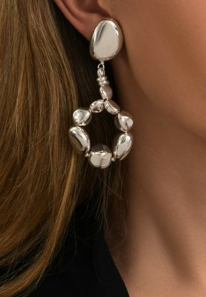 Boucles d'oreilles en argent avec un design circulaire texturé, agrémentées de perles lisses et rondes de différentes tailles et d'une finition polie.