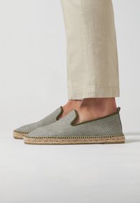 Espadrilles con parte superior de tela a cuadros en verde y blanco, aberturas laterales elásticas y suela de cuerda de yute natural. Diseño de perfil bajo y tipo slip-on.