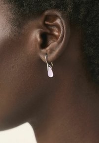 Hopehopea hopea hopea hopeailta, jossa on vaaleanpunainen pisaramuotoinen ripustus. Ripustus on huurrettu, mikä tuo esiin sileän pinnan ja hienovaraiset värivaihtelut.