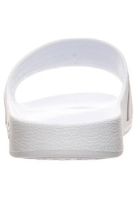 Bílé žabky s texturovanou gumovou podrážkou a hladkým designem thong popruhu. Celkový tvar je jednoduchý a zakřivený.