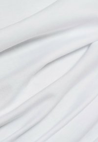 Weißer Stoff mit weicher Textur, der glatte Falten und einen leichten Glanz aufweist. Das Material wirkt leicht und dehnbar, mit einer sauberen, einfarbigen Optik.
