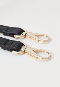 Black nylon strap with gold-tone metal hardware. Features engraved "VALENTINO" on the clips. Smooth, durable texture and sturdy design.