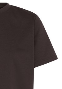 Gros plan d’un t-shirt uni marron foncé à manches courtes, montrant le haut de la poitrine, l’épaule et la manche sur fond blanc.