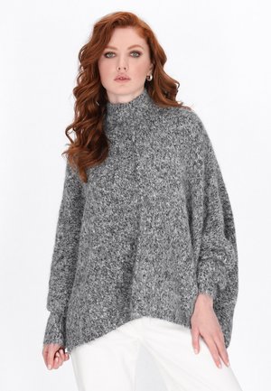 Maglione grigio a maglia con colletto alto, maniche ampie e orlo irregolare. La texture morbida e il dettaglio in filato spesso sono ben visibili.