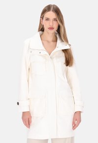 Hvid letvægtsjakke med høj krave, lynlås foran, to store brystlommer og knapremme på ærmerne. Glat tekstur.