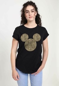 Camiseta negra con un diseño de cabeza de Mickey Mouse en estampado de leopardo dorado. Mangas cortas, escote redondo y ajuste relajado. Pantalones vaqueros de color azul claro.