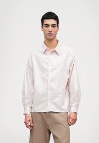 Svetlo ružová košeľa na gombíky s tenkými bielymi pruhmi, s klasickým golierom, dlhými rukávmi a hladkou, mierne lesklou textúrou.