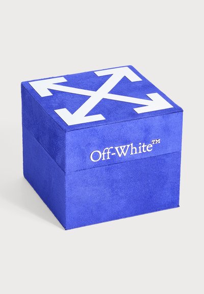 Boîte bleue et blanc cassé avec un motif blanc de flèches entrecroisées sur le couvercle, présentée sur un fond clair uni.