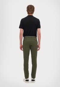 Olivenfargede chinos med tilpasset passform, i bomull, og to baklommer. Kombinert med en sort skjorte med korte ermer og hvite sneakers.