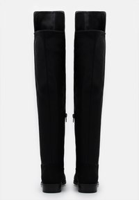 Botas negras de muslo alto con un material superior liso, detalles de costura sutiles y cremalleras laterales. La base presenta un acento de ante texturizado.