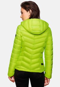Lime green puffer jacket with a hood, featuring chevron quilted pattern and elastic cuffs, paired with slim black pants.