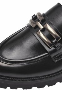 Mocassin en cuir noir avec semelle épaisse et détail boucle rectangulaire argentée sur le dessus.