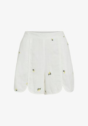 Hvite lin-shorts med bølgete kant og små gule sitronbroderier spredt over stoffet.