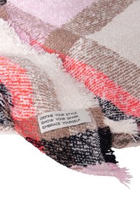 Coperta lavorata a maglia con quadri rosa, arancione, marrone e nero, con bordi sfrangiati. Etichetta con istruzioni per la cura e testo motivazionale.
