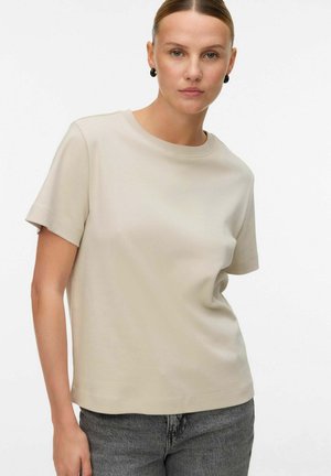 Beige kortærmet t-shirt med rund halsudskæring. Blødt, glat stof med en afslappet pasform, parret med grå jeans. Ingen synlige mønstre eller udsmykninger.