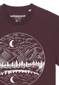 T-shirt bordeaux avec un graphisme circulaire blanc représentant des montagnes, des arbres, un lac réfléchissant et des nuages, avec une lune croissante au-dessus.