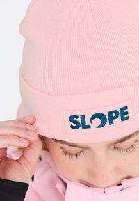 Vaaleanpunainen neulepipo, jossa on käännehelma, ja jossa on suora malli, jossa lukee "SLOPE" tummansinisellä brodeerauksella. Pehmeää, teksturoitua materiaalia.