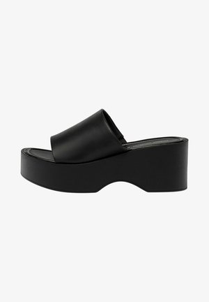 Sandalia de plataforma negra con una amplia tira lisa, punta redondeada y una suela gruesa y curvada. Hecha de material sintético, con un acabado mate.