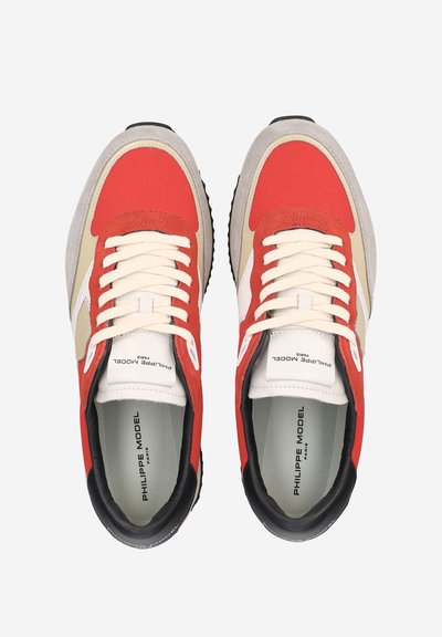 Paire de baskets rouges, beige et blanches avec des accents noirs, des lacets crème et l'inscription "Philippe Model Paris" imprimée sur la semelle intérieure et la languette.