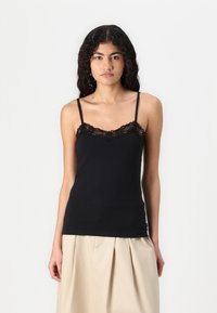 Svart cami laget av myk stoff med blonderkant langs halsudskjæringen og tynne justerbare stropper. Enkel, tettsittende design.