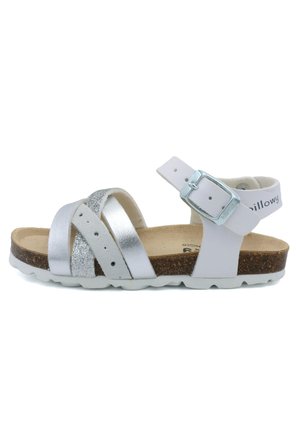 Sandales argentées et blanches avec des brides croisées, une surface texturée, une boucle réglable et une semelle en liège marron. Semelle extérieure en caoutchouc blanc solide.