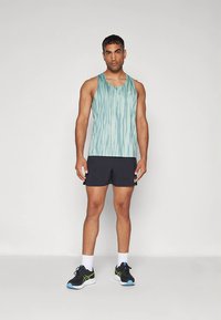 Maiou bleu deschis cu dungi verticale, asortat cu pantaloni scurți negri. Poartă pantofi sport negri cu accente verzi și șosete albe.