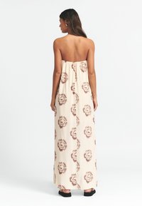 Olkaimeton maksimekko vaaleanbeigellä värillä ja ruskeilla kukkakuvioilla. Kevyt kangas, rento malli, nilkkapituisuus ja kerätty yläosa.