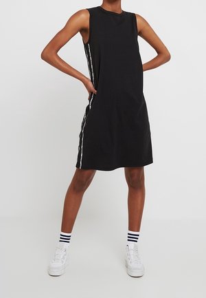 Robe noire sans manches avec une coupe ample, présentant des détails rayés blancs sur les côtés, fabriquée en tissu de coton doux.