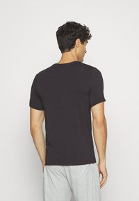 T-shirt nera a maniche corte realizzata in tessuto morbido, con scollo rotondo e vestibilità comoda, mostrata da dietro.