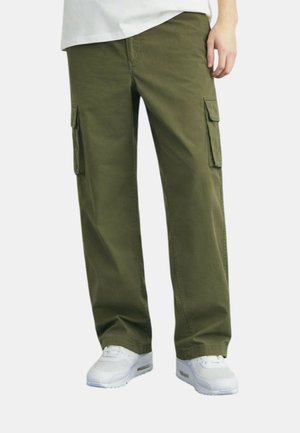 Coppia di pantaloni cargo verde oliva con tasche a patta, indossati con sneaker bianche e camicia bianca, mostrati dalla metà coscia ai piedi.