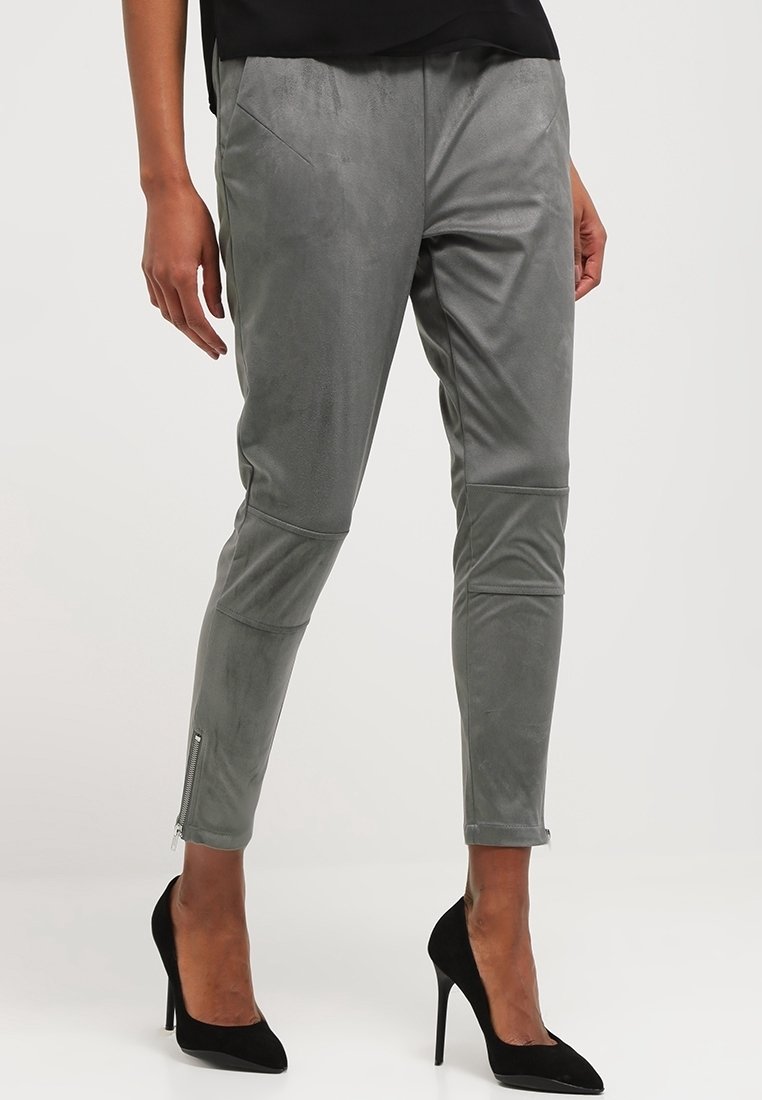 Grijze nepsuede broek met een slim fit, enkelritsen en twee voorkeuken, gecombineerd met zwarte hoge hakken. Gladde textuur en op maat gemaakte ontwerp.