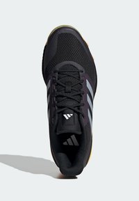 Zapatilla deportiva negra con parte superior de malla texturizada, franjas grises, cordones negros y suela de goma; cuenta con un collar acolchado y detalles del logo.