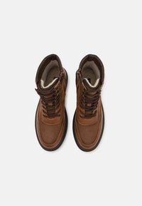 Botas de tobillo de cuero marrón con cuello acolchado, puntera redonda, cordones en el frente y cremallera lateral. Interior forrado con tela suave para mayor calidez.