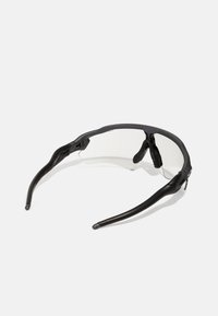 Schwarze Sportsonnenbrille mit flexiblem Rahmen, klaren Gläsern und gummierten Akzenten an den Nasenpolstern und Bügeln für einen sicheren Sitz.