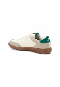 Zapatilla de cuero blanco con acentos de ante gris, pestaña en el talón verde y suela de goma. Presenta un diseño clásico de cordones y perforaciones.
