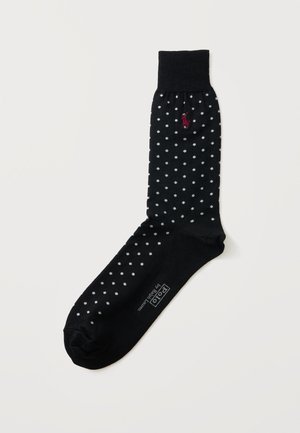 Chaussette noire à pois blancs, bord-côte, logo rouge brodé près du haut et texte blanc "Polo by Ralph Lauren" sur la semelle du pied.