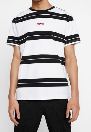 Hvid bomuld t-shirt med vandrette sorte striber, rund halsudskæring og lille rød Levi's-logo på brystet. Korte ærmer, afslappet pasform.