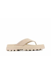 Beige flip-flop sandaali, jossa on mokkanahkainen yläosa, paksu uritettu pohja ja logon kohokuviointi hihnassa. Suunniteltu mukavuutta ja kestävyyttä varten.