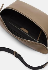 Brązowa skórzana torba z zamkiem błyskawicznym, z czarnym wnętrzem i dodatkowymi kieszeniami na zamek. Solidny pasek z tkaninowymi akcentami.