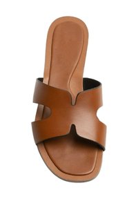 Sandelia plana de cuero marrón con un diseño recortado, suela plana y una textura suave con un estilo minimalista.